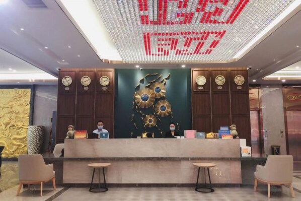 A reception desk with a digital clock display, wooden paneling, and a decorative wall piece. - Yu Long Jin Hotel (Ezhou)