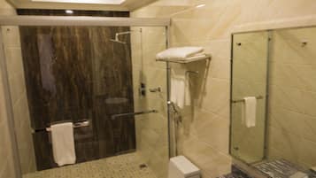 Une salle de bain moderne avec une douche à parois de verre, des toilettes blanches et un lavabo en marbre.
