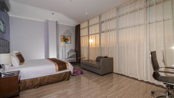 Ein Hotelzimmer mit Bett, einer Couch, einem Schreibtisch und einem Sessel.