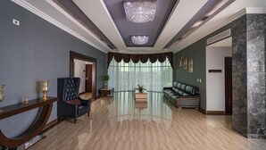 Un hall d’entrée spacieux doté d’un sol en marbre, d’un lustre, d’un canapé et d’une console ornée d’objets décoratifs.