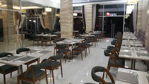Un restaurant moderne doté d’une grande salle à manger, de colonnes en marbre et offrant une vue sur la rue.