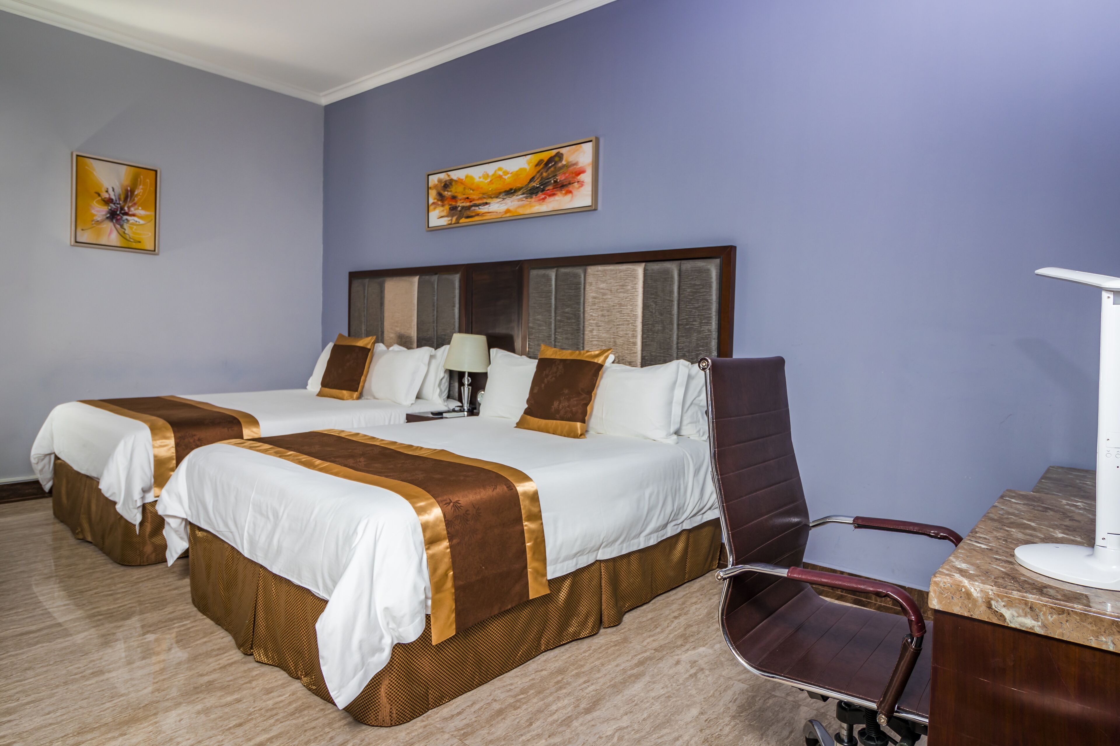 Habitación de hotel con dos camas, un escritorio y una silla.