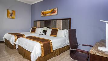 Habitación de hotel con dos camas, un escritorio y una silla.