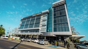 Un hôtel moderne doté d’une façade en verre, d’une entrée couverte et d’une enseigne indiquant « City Plaza ».