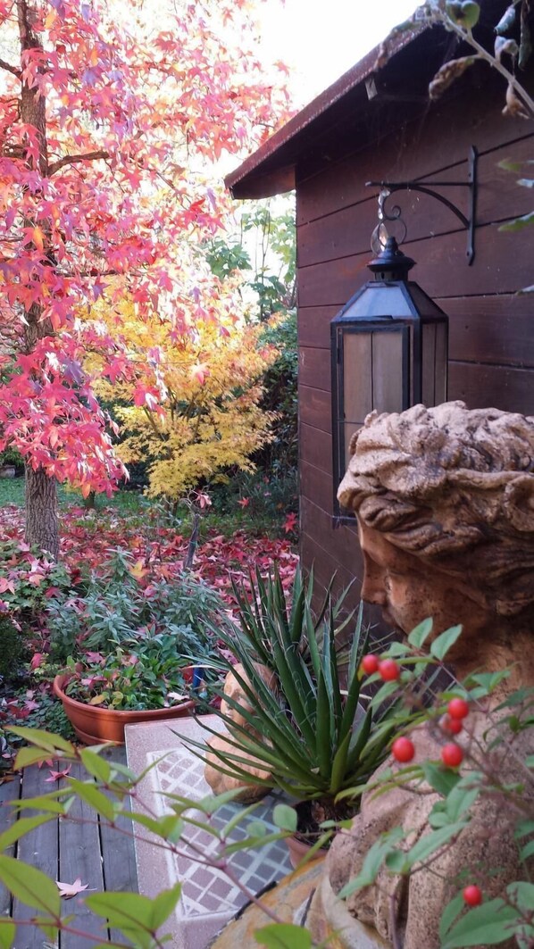 A garden with a stone statue, a lantern, and various plants.