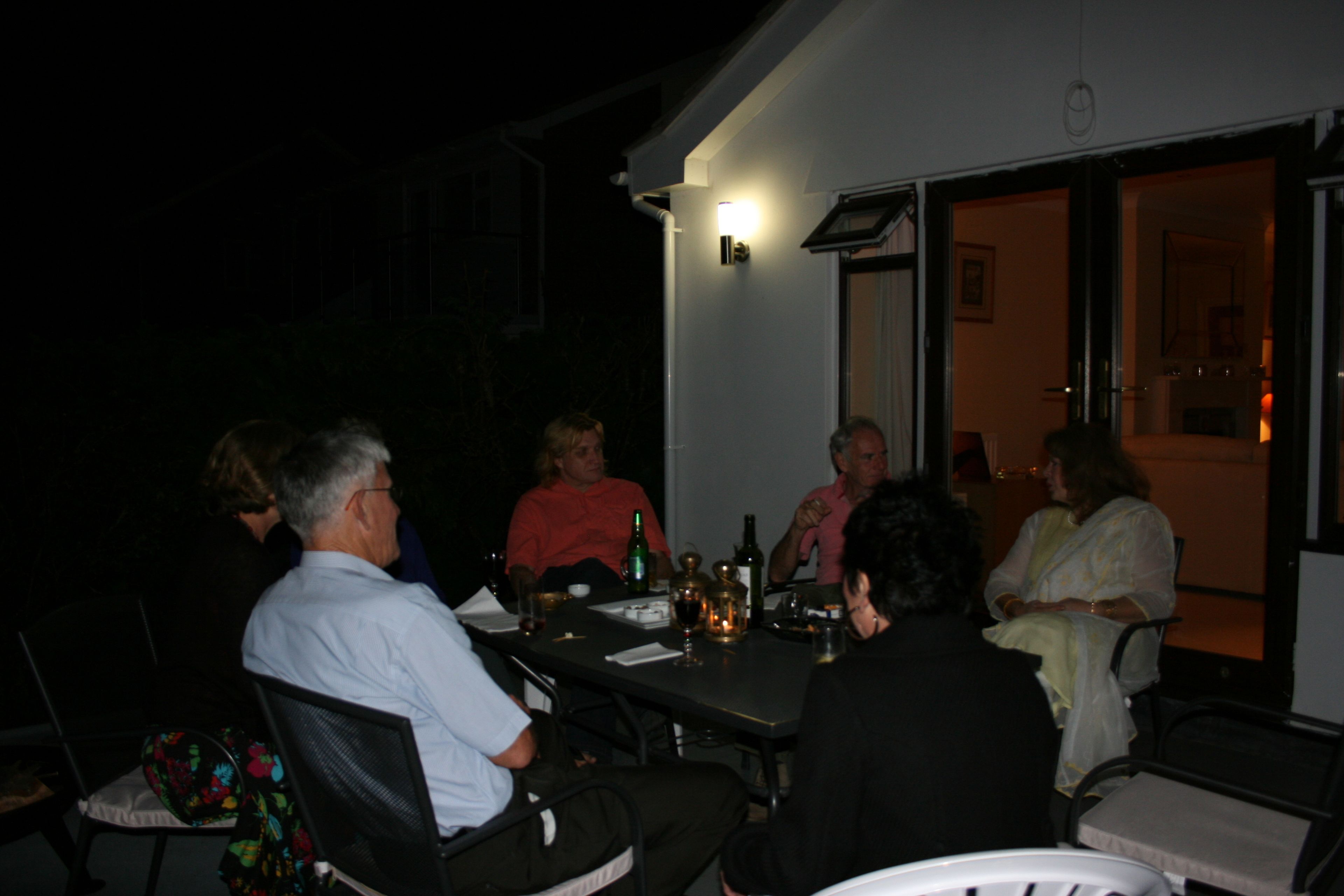A group of people seated around a table outdoors at night.