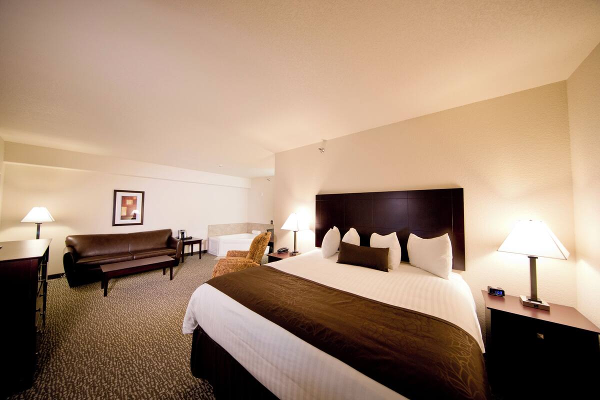 Une chambre d’hôtel avec un grand lit, un canapé, un bureau et deux lampes.