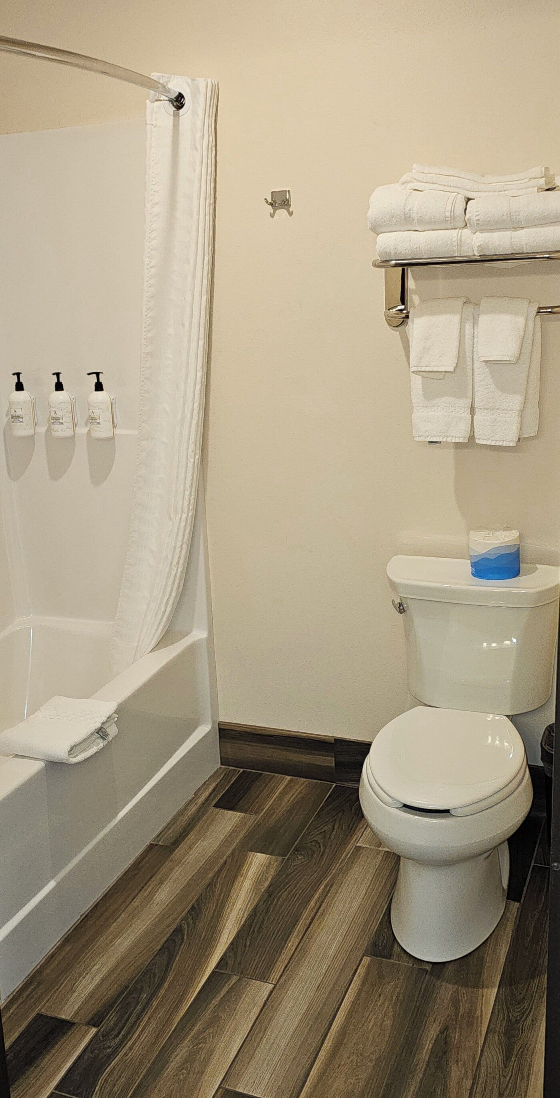 Ein Badezimmer mit Badewanne, Toilette und einem Handtuchhalter mit gefalteten Handtüchern.