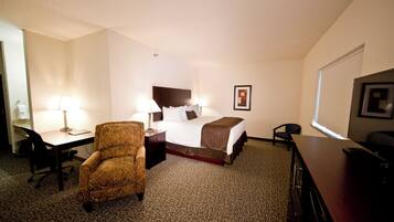 A hotel room with a bed, desk, chair, and lamps.