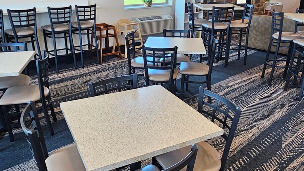 A restaurant with multiple tables and chairs, a stone fireplace, and framed artwork on the walls. - Cobblestone Inn & Suites – Manchester (Manchester)