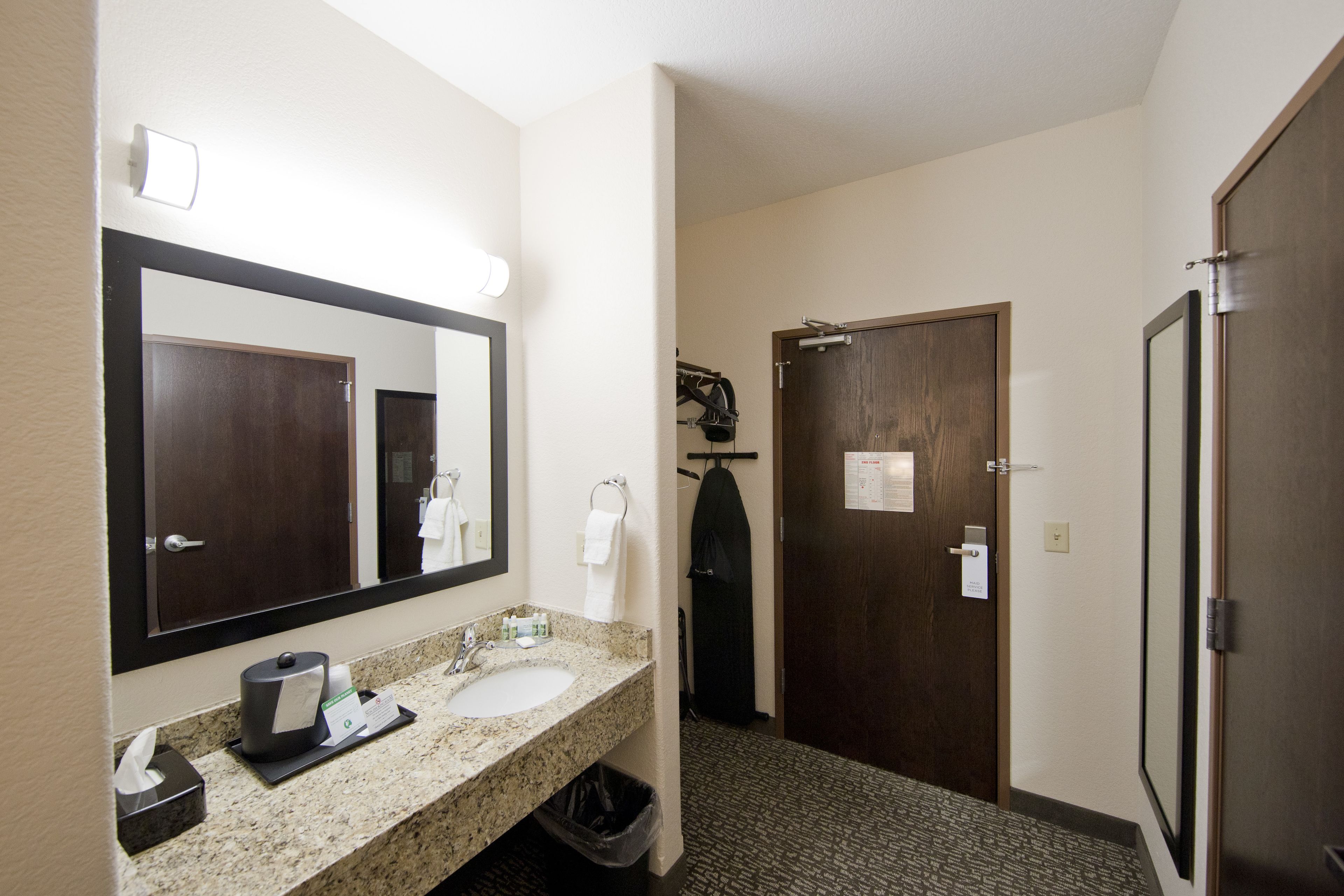 A hotel bathroom with a sink, mirror, and two doors.