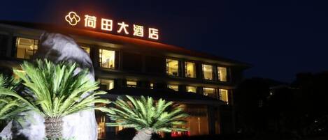 A hotel with a prominent sign, large windows, and well-maintained landscaping.