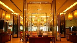 Un moderno vestíbulo de hotel con un mostrador de recepción central, zona de estar e iluminación ambiental.
