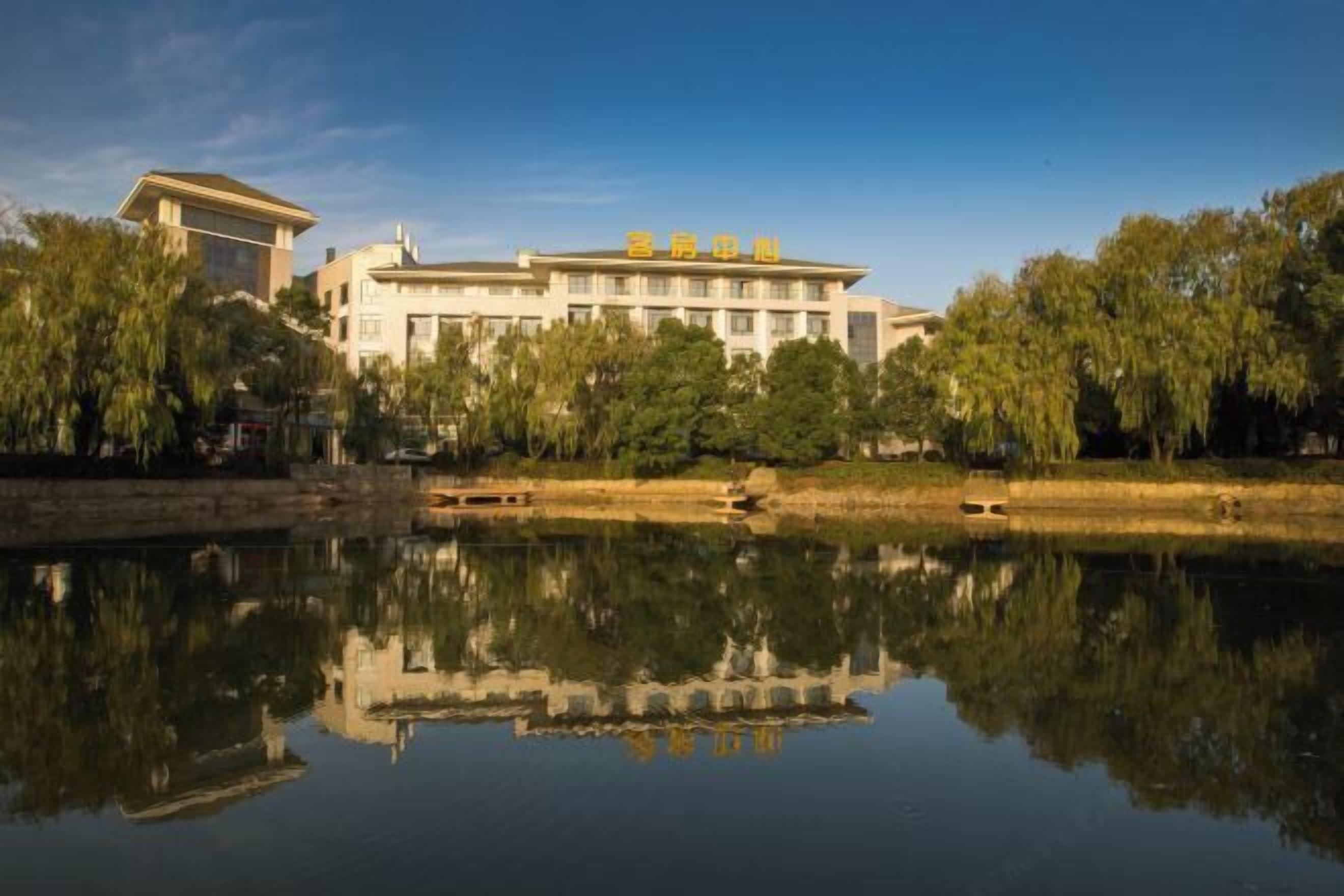 A hotel with a reflection in the water, surrounded by trees.