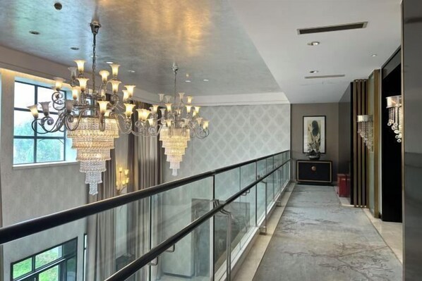 A spacious hallway with a glass railing, a large chandelier, and a marble floor. - Hetian Hotel (Wuhan)