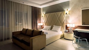 A modern hotel room with a large bed, a sofa, a desk, and a chair. - Monte Bianco (Astana)