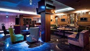 A modern lounge area with seating, a bar, and a television screen. - Monte Bianco (Astana)