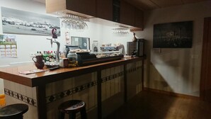 A bar area with a counter, stools, a coffee machine, and various bottles. - El camino de Santovenia - Albergue - Hostel (Arlanzon)