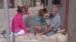 A man and a woman sitting by a small pool with a flag on the man's shirt. - El camino de Santovenia - Albergue - Hostel (Arlanzon)