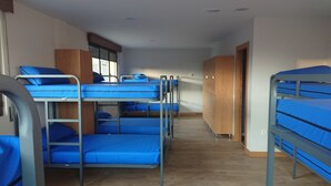 A dormitory room with bunk beds, wooden cabinets, and a carpeted floor. - El camino de Santovenia - Albergue - Hostel (Arlanzon)