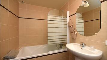 Un baño moderno con bañera, lavamanos y espejo.