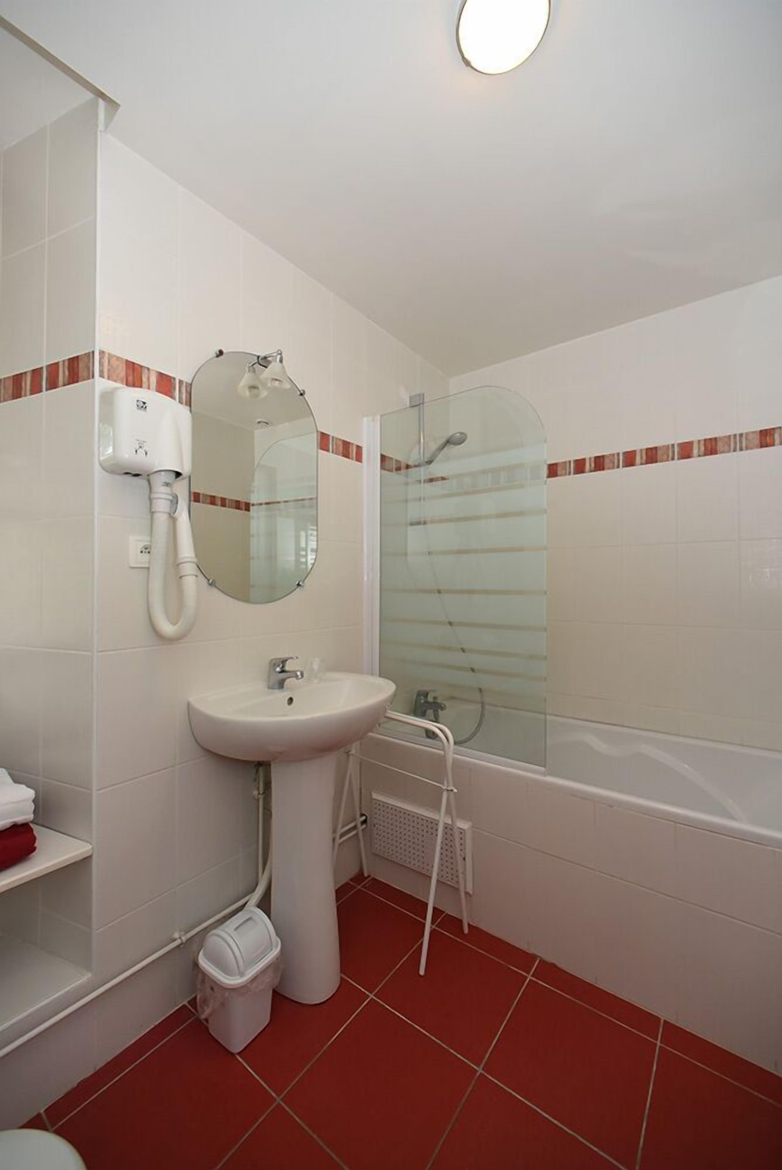 A bathroom with a sink, mirror, toilet, and shower.