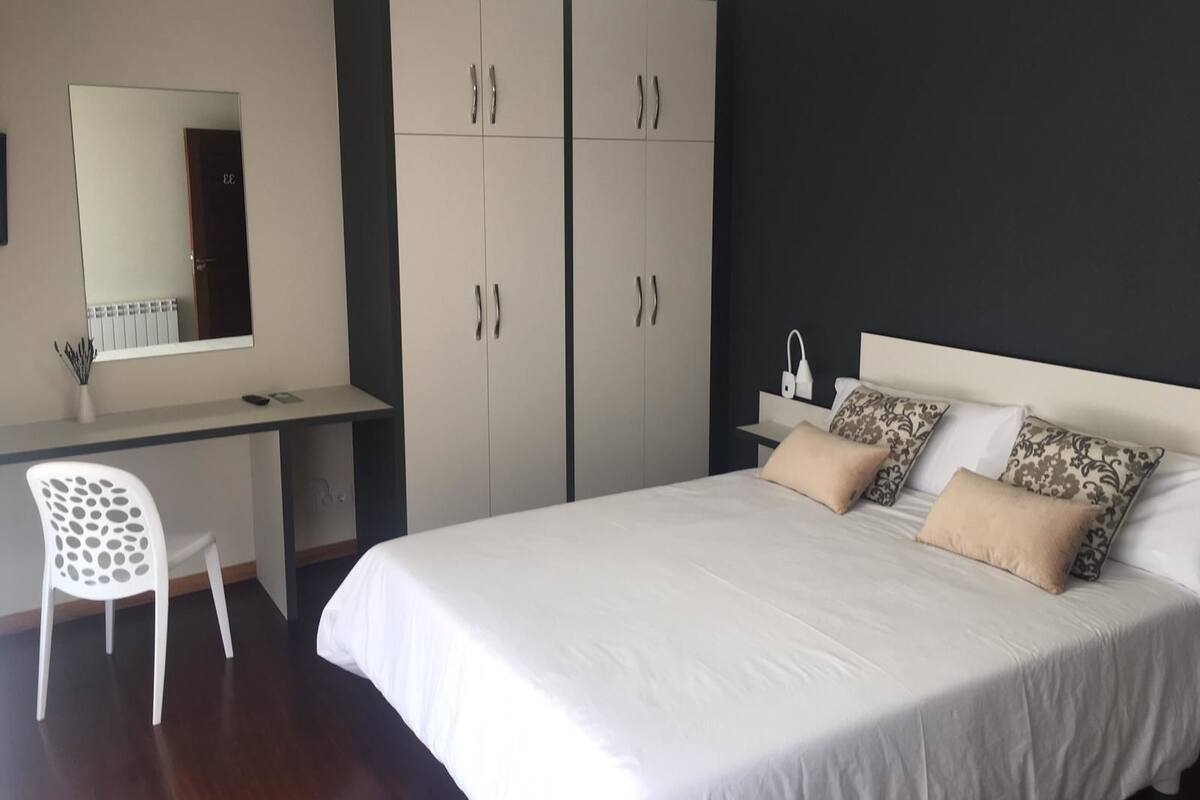 A bedroom with a bed, a desk, and a wardrobe.