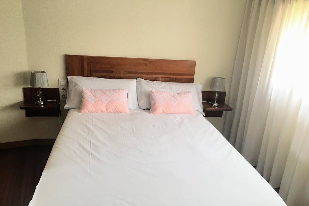 A hotel room with a large bed, two bedside tables with lamps, and a wooden headboard.