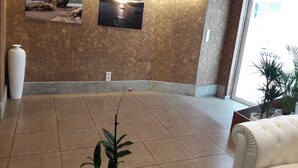 A lobby with a tiled floor, a white vase, and two framed pictures on the wall. - Hostal Vendaval (Ortigueira)