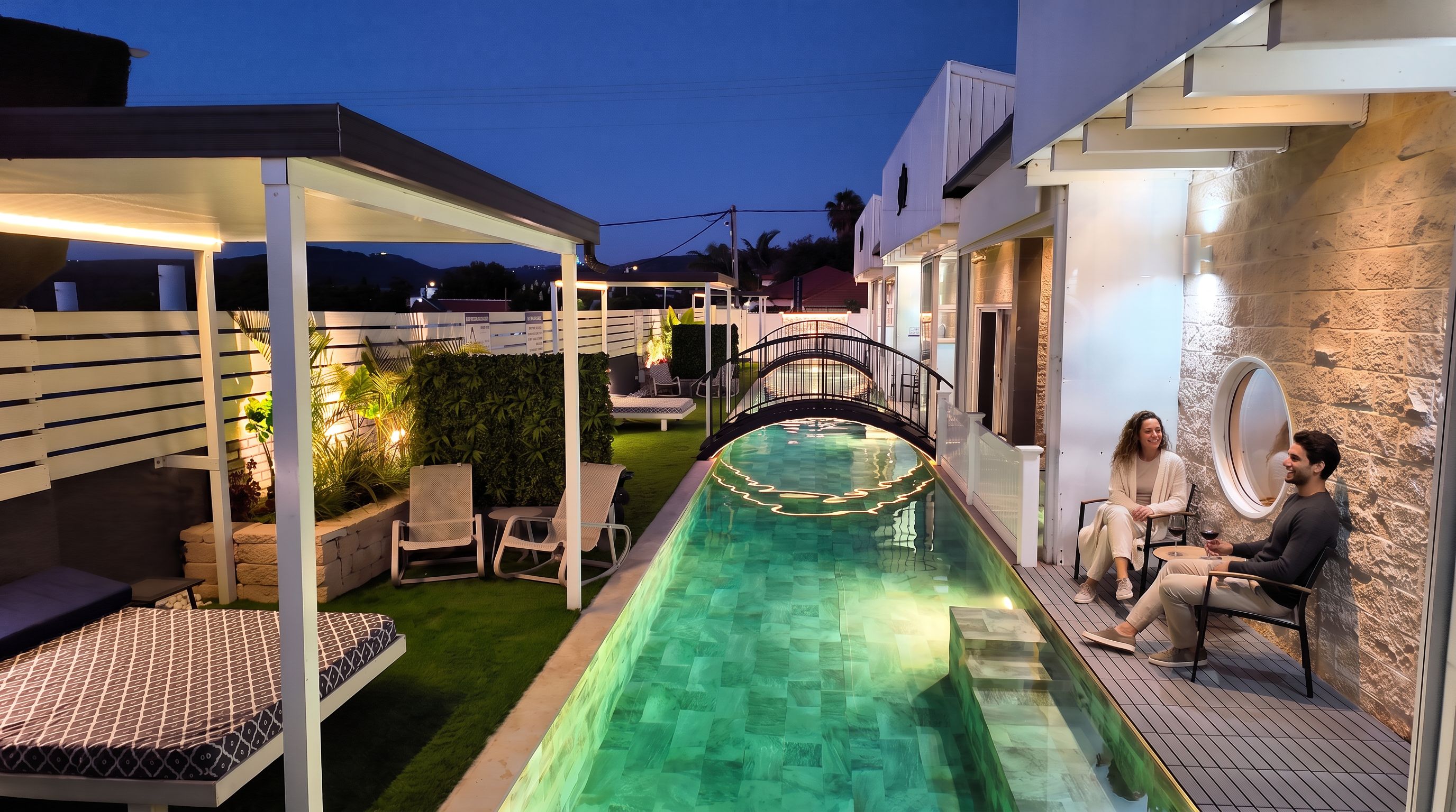 A swimming pool with a bridge, outdoor seating, and a stone wall.