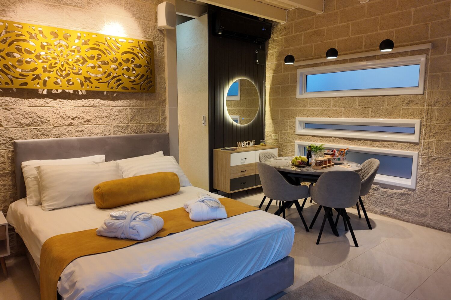 Una habitación de hotel con una cama, un escritorio con una silla, un espejo y una ventana.