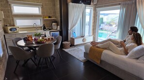 A modern living space with a dining area, a sofa with a view, and a kitchen with a microwave and coffee machine. - Ahuzat Maya (Ma'ale Yosef)