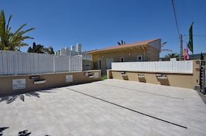 Ein Gebäude mit einem Ziegeldach und einem weißen Zaun. Schilder sind am Zaun angebracht und es gibt eine kleine Gartenanlage mit Pflanzen.