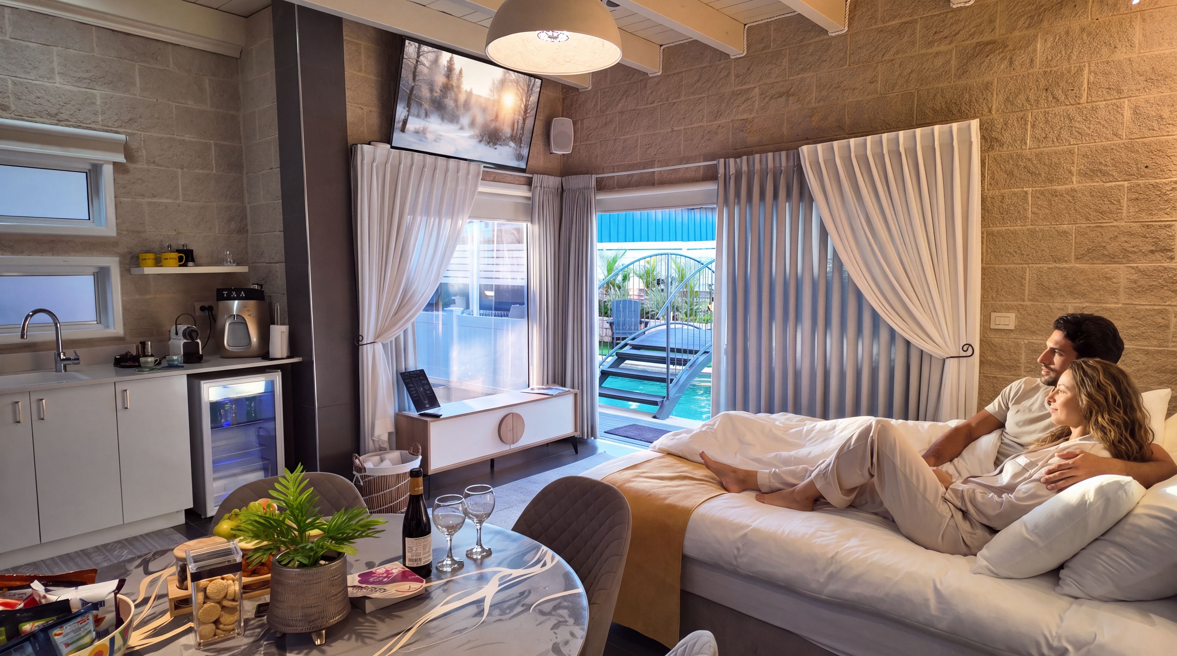 Una moderna camera d'albergo con divano, un tavolo da pranzo con una pianta, un portatile e vista su una piscina.