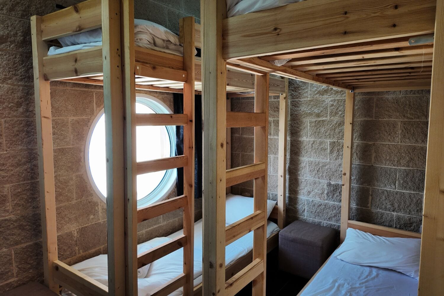A bunk bed room with a skylight, stone walls, and a small bench.