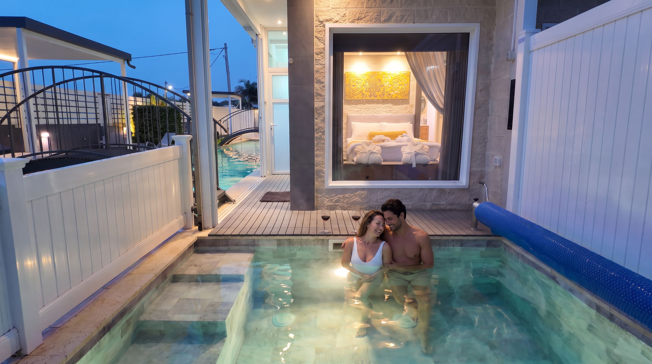 Un couple dans un jacuzzi, avec vue sur une chambre et une piscine.
