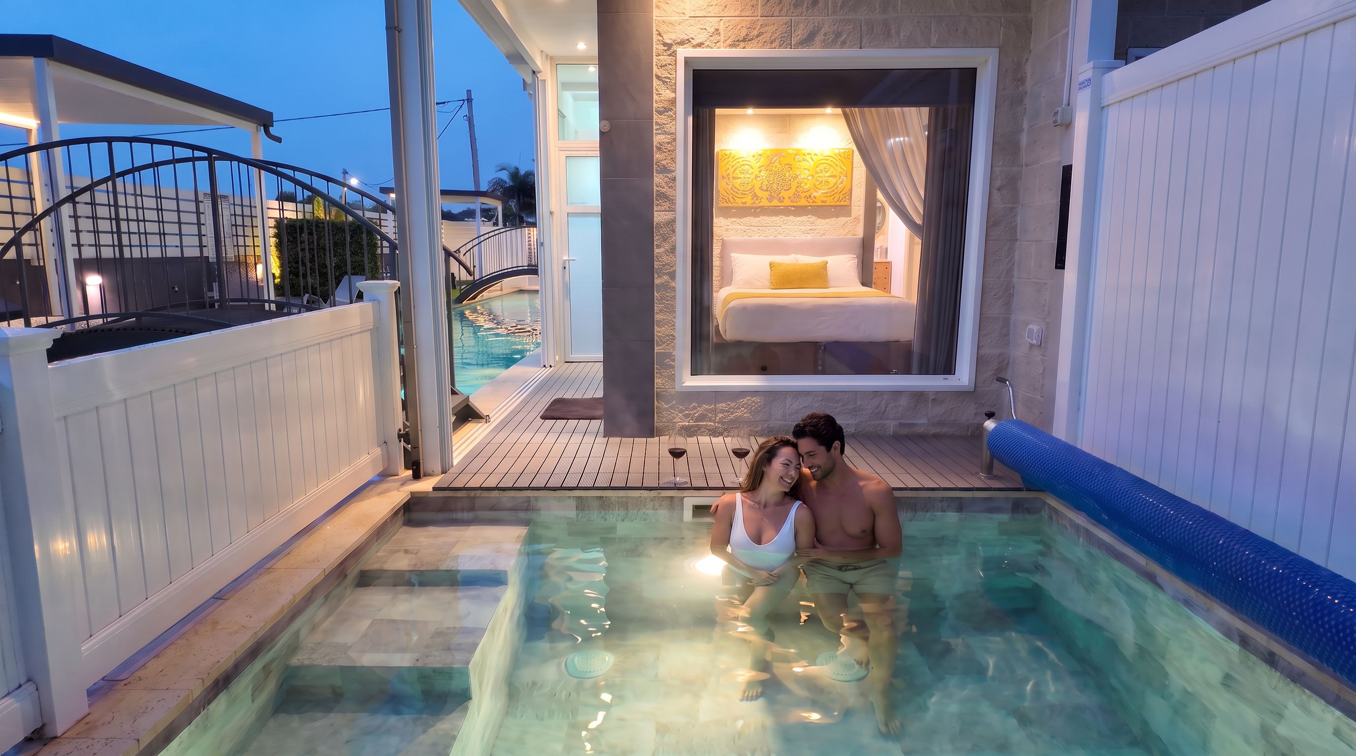 Una pareja en un jacuzzi con vistas a un dormitorio y una piscina.