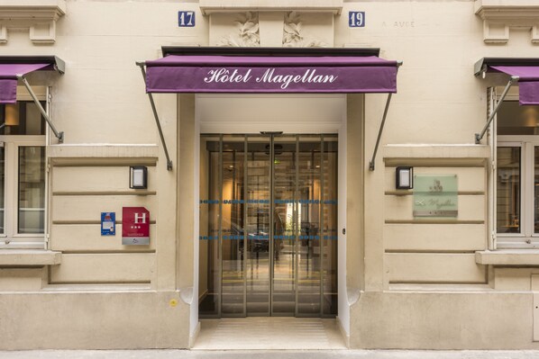 The entrance to Hotel Magellan with a glass door and a purple awning. - Hotel Le Magellan (Paris)