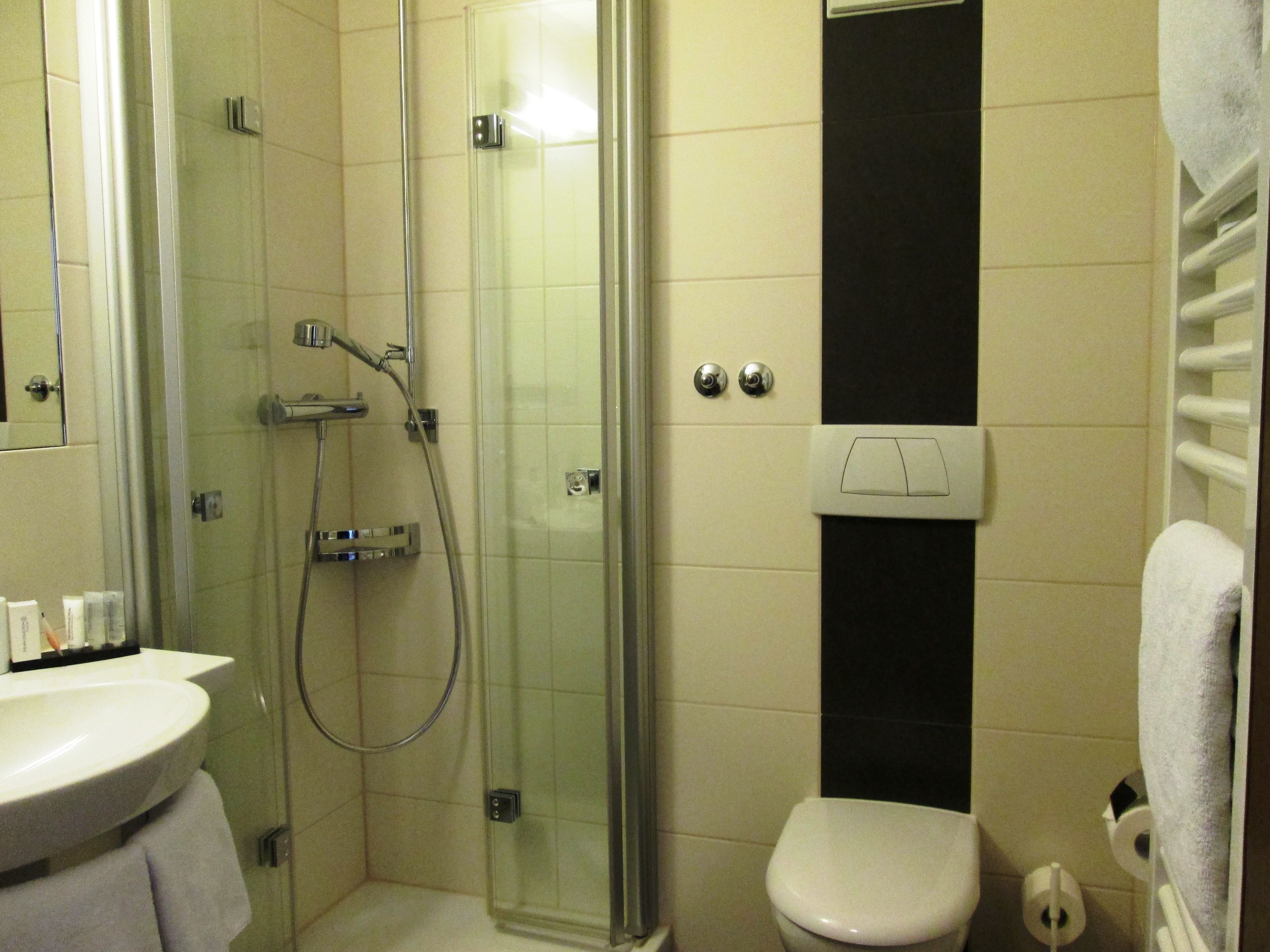 Un baño con ducha de vidrio, un lavamanos blanco y un inodoro.