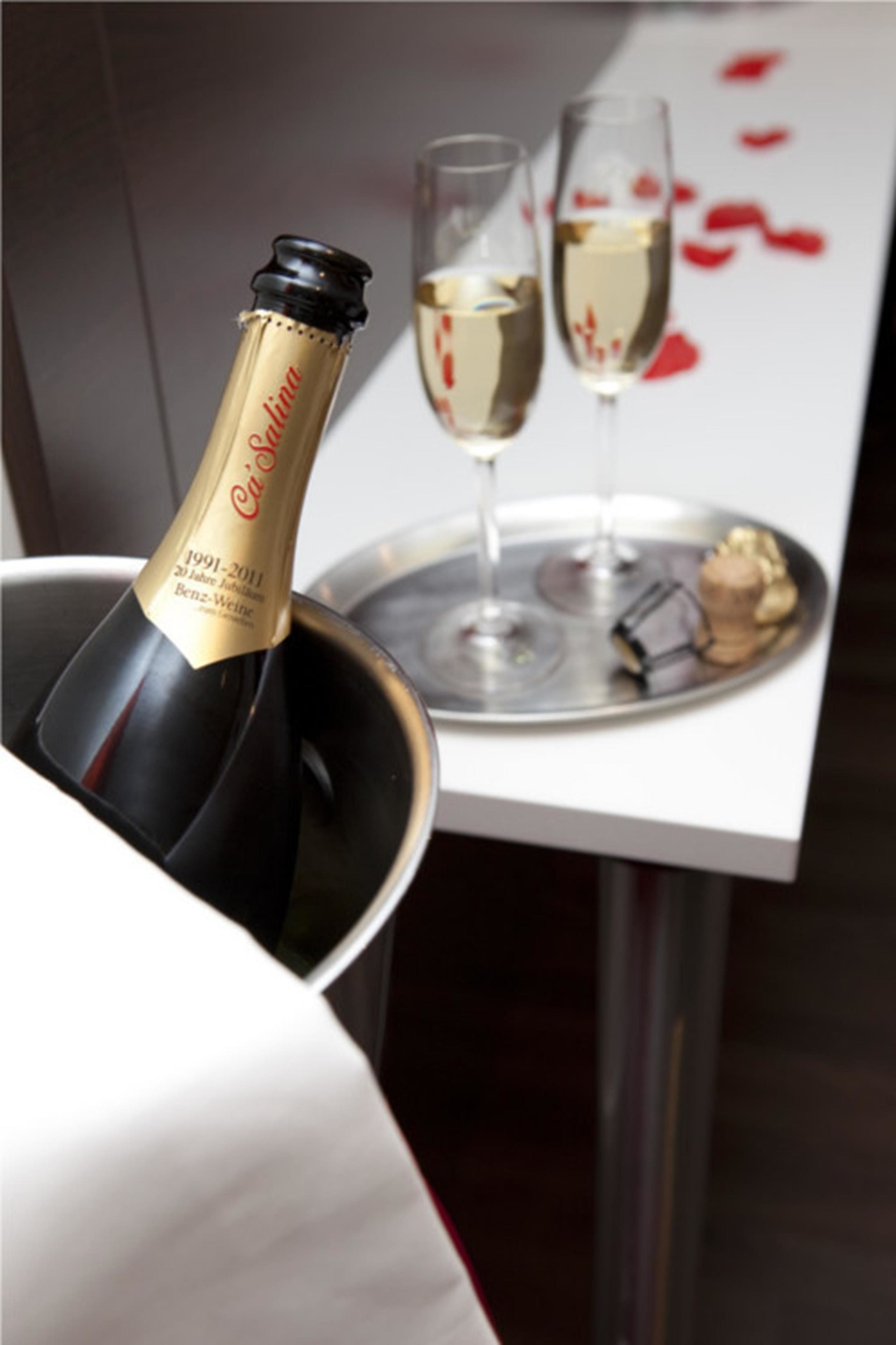 A bottle of wine in a bucket, two glasses of wine on a tray, and a table with a red design.