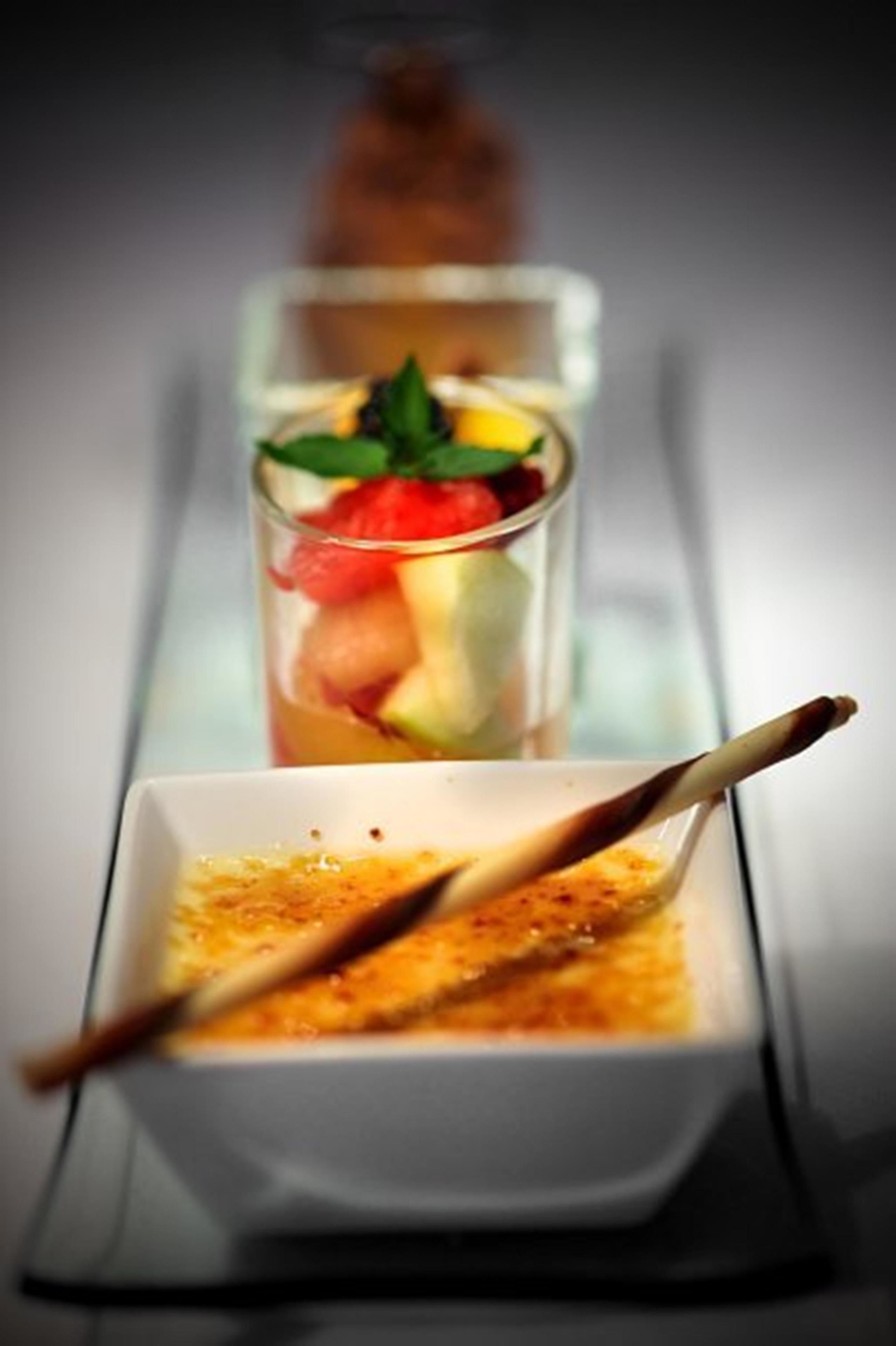 Presentación de postres con ensalada de frutas y un postre de chocolate en recipientes separados.