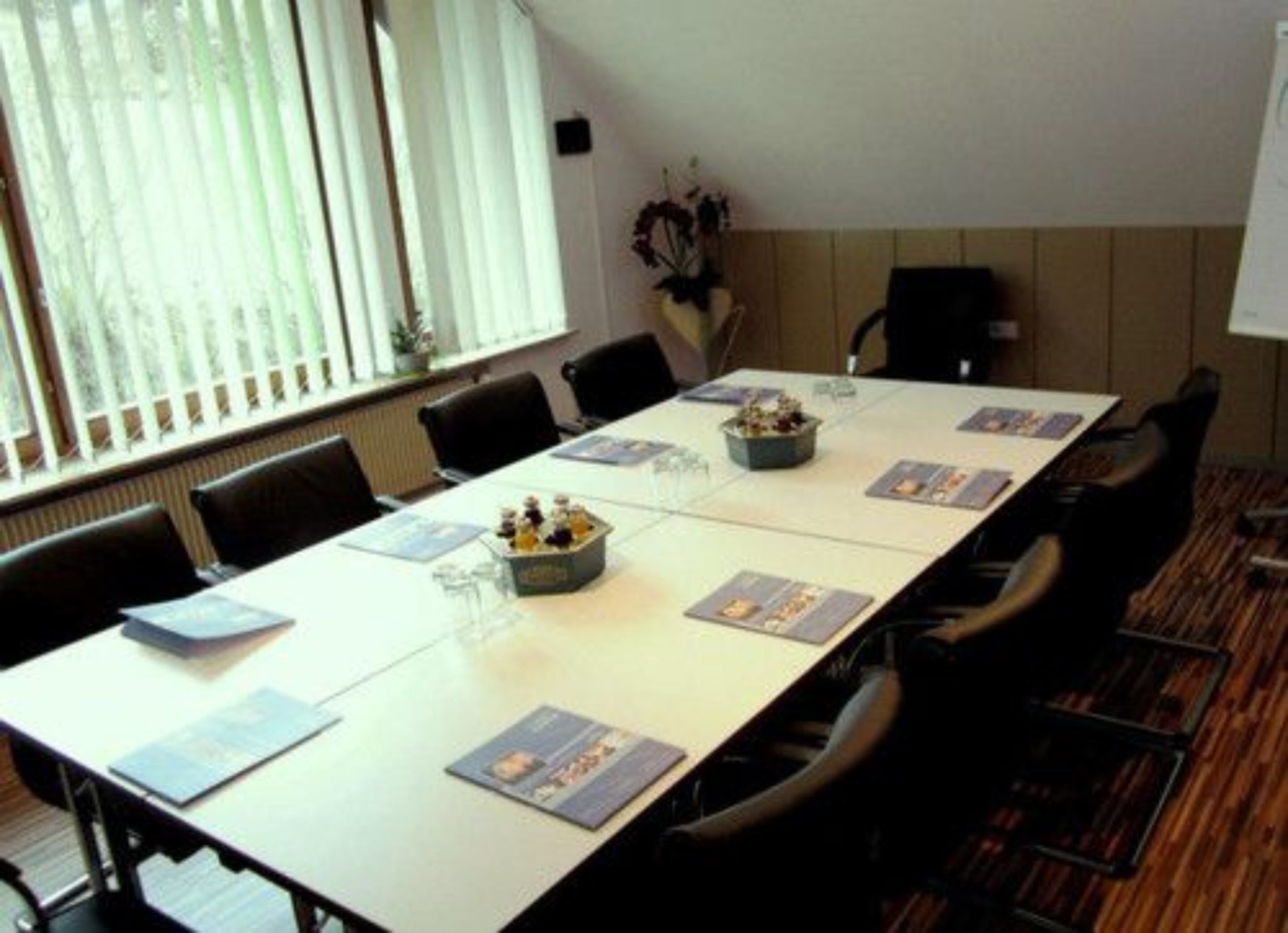 A conference room with a long table, chairs, and a whiteboard.