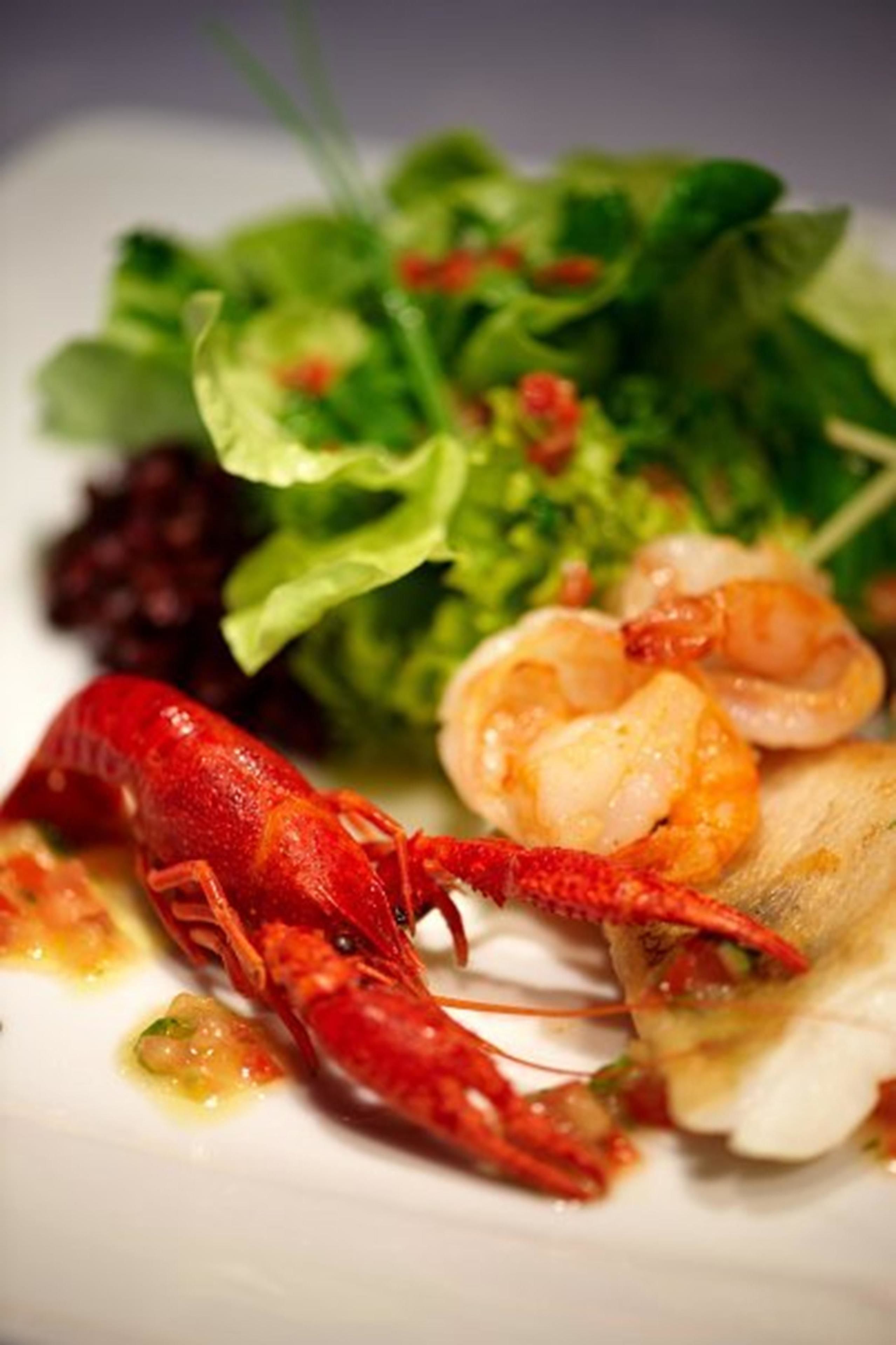 A plate with a lobster tail, shrimp, and greens.