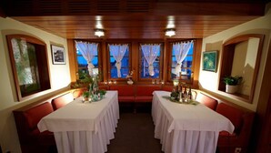 A dining area with two tables set for a meal, wooden ceiling, and windows with curtains. - Hotel Restaurant Kaiser (Herrenberg)