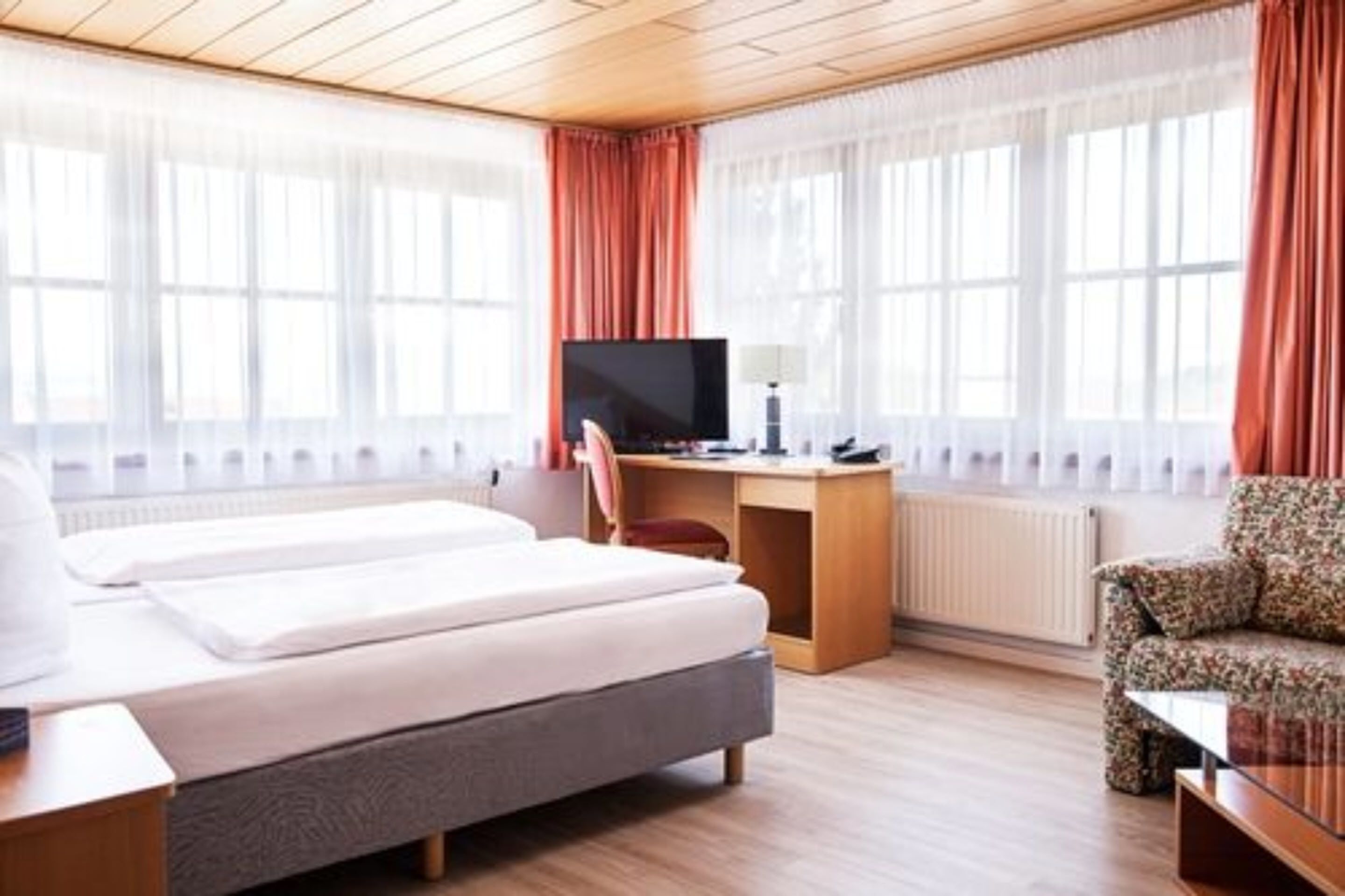 A hotel room with a bed, a desk with a computer, a chair, and a sofa.