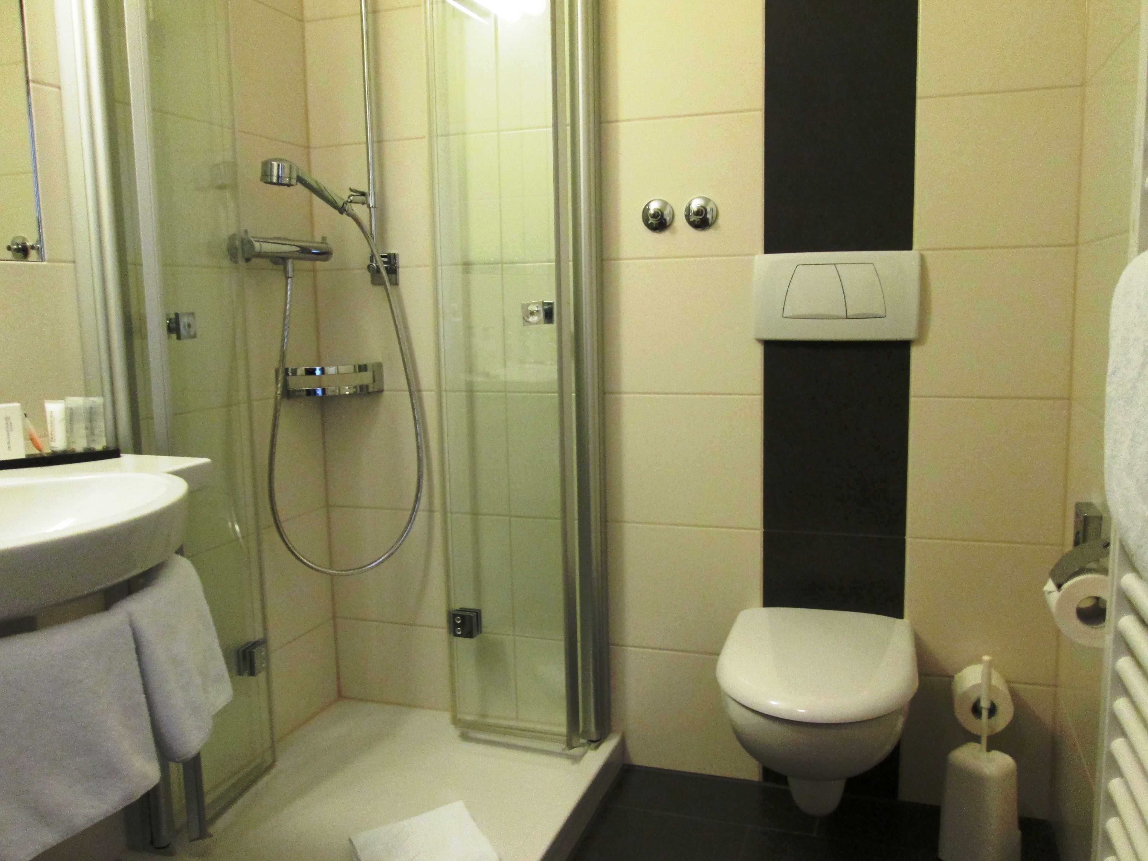 A bathroom with a glass-enclosed shower, a toilet, and a sink.