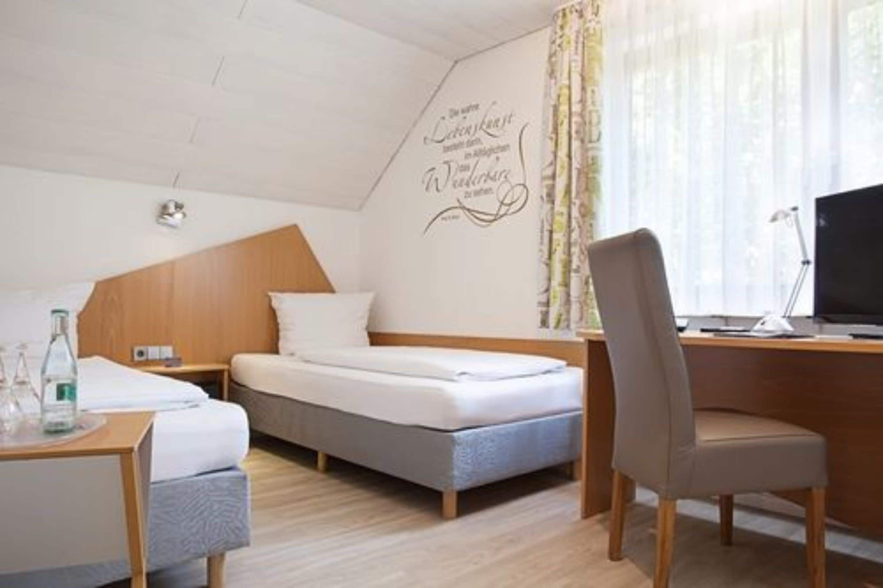 Een hotelkamer met een bed, een bureau, een stoel en een raam met gordijnen.
