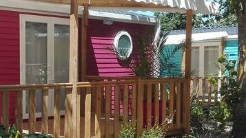 A row of colorful mobile homes with a wooden deck and a glass door.