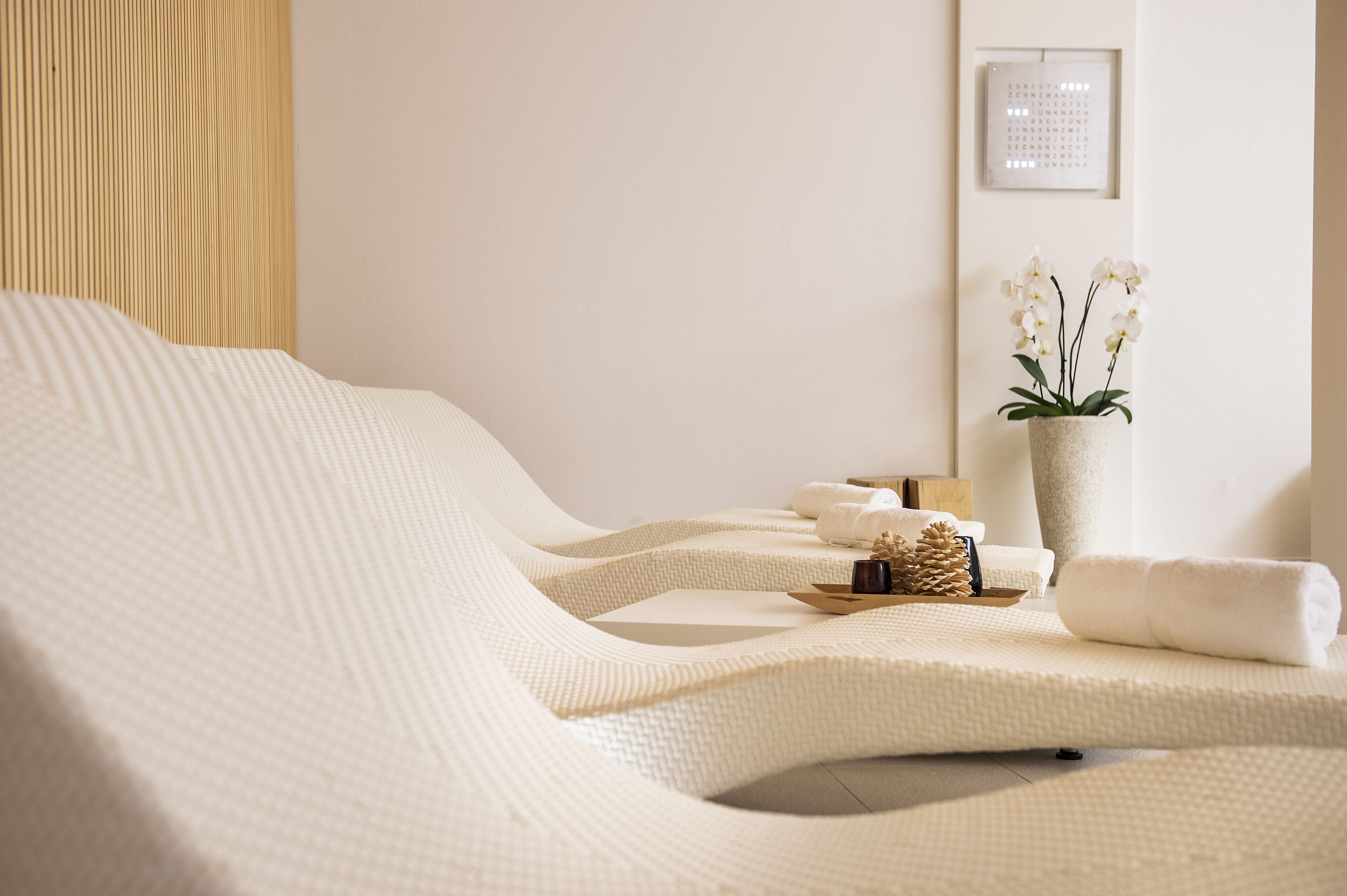 Une salle de spa avec un lit de massage incurvé, une orchidée en pot et un tableau encadré au mur.