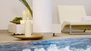 A spa area with a hot tub, candles, a bowl of fruit, and a lounge chair. - Hotel Rössle (Galtur)